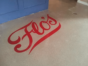 the word flo 's is painted on the floor of a room .