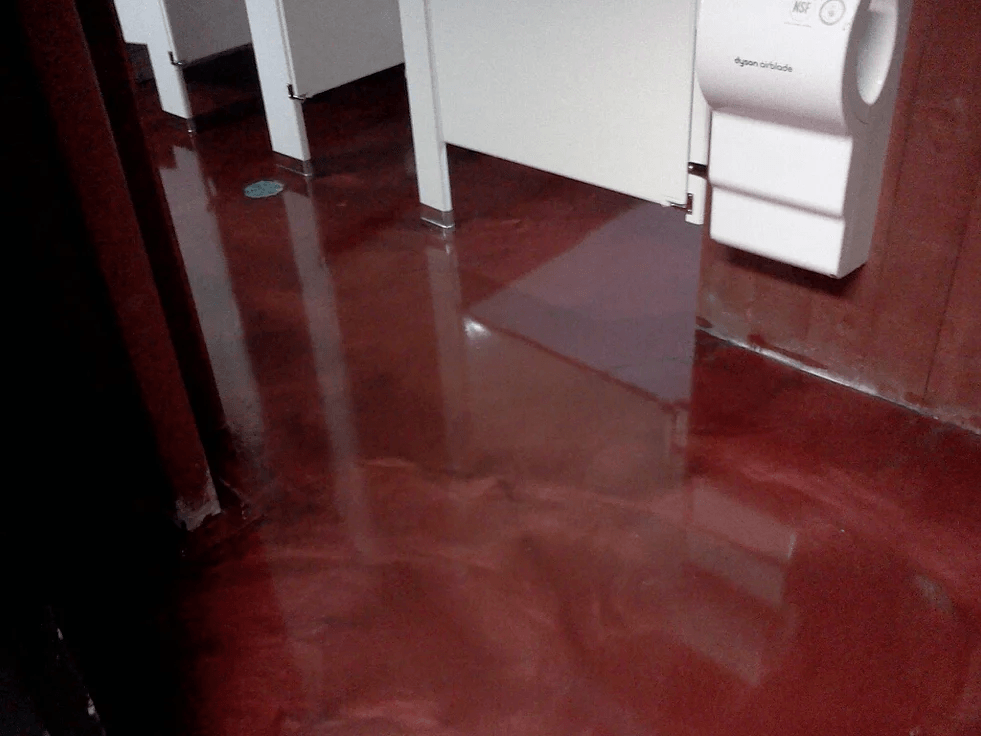 a bathroom with a red floor and a hand dryer