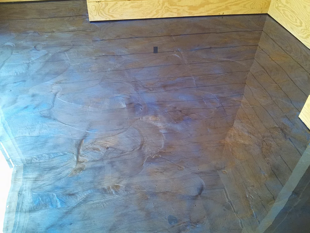 a shiny concrete floor in a room with a wooden wall .