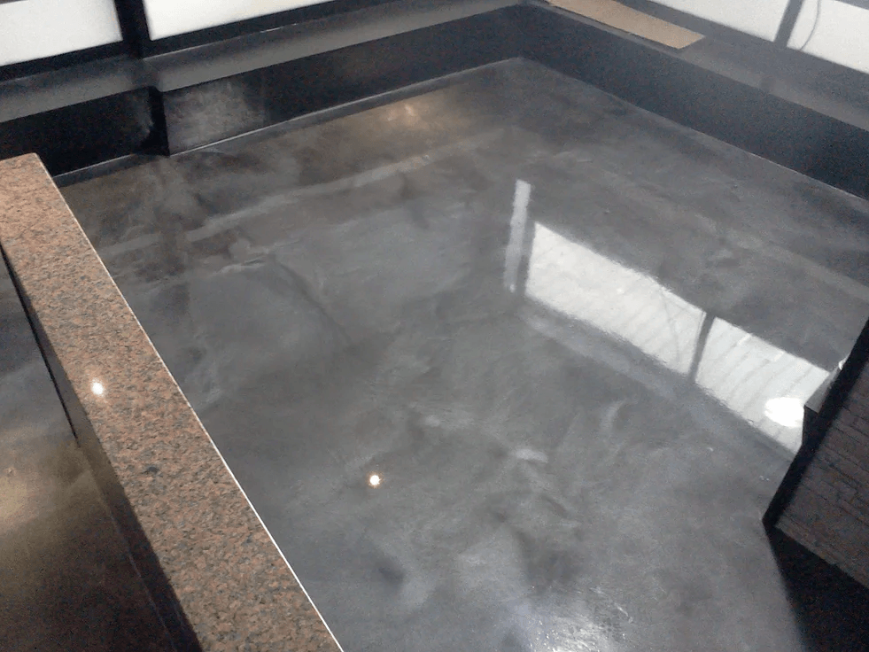 a bathroom with a shiny concrete floor and a granite counter top