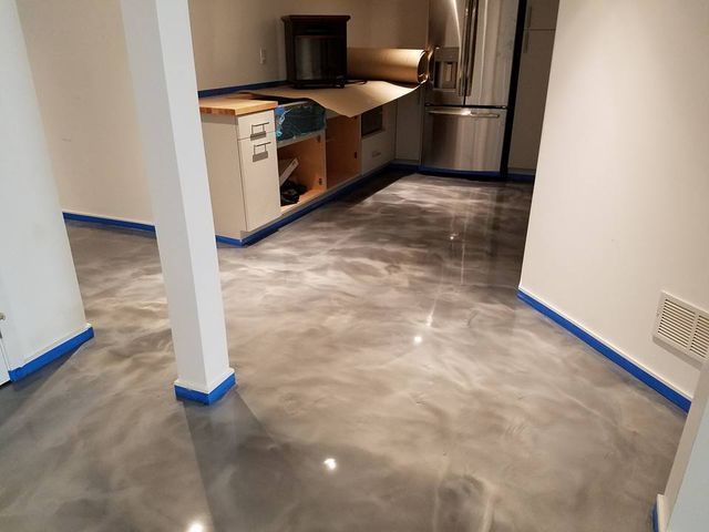 a kitchen with a shiny metallic floor and a stainless steel refrigerator .