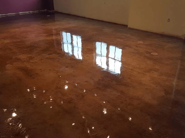 a room with a shiny concrete floor and a reflection of windows .