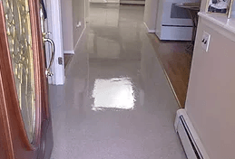 a long hallway leading to a kitchen and a stove in a house .