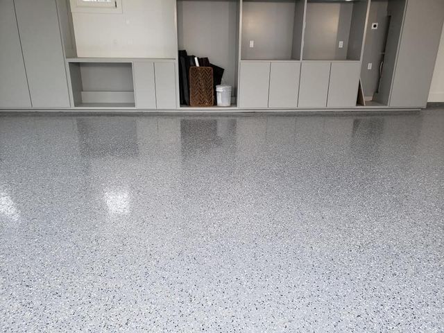 a garage with a gray floor and white cabinets .