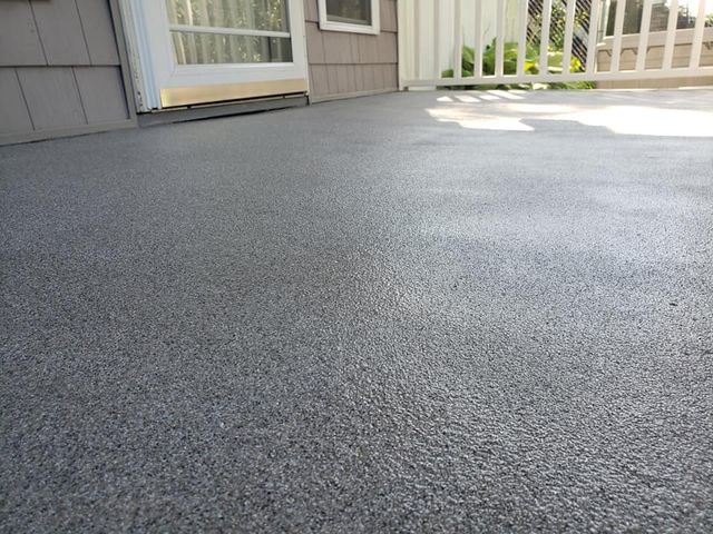 a gray concrete deck with a white railing and a sliding glass door .