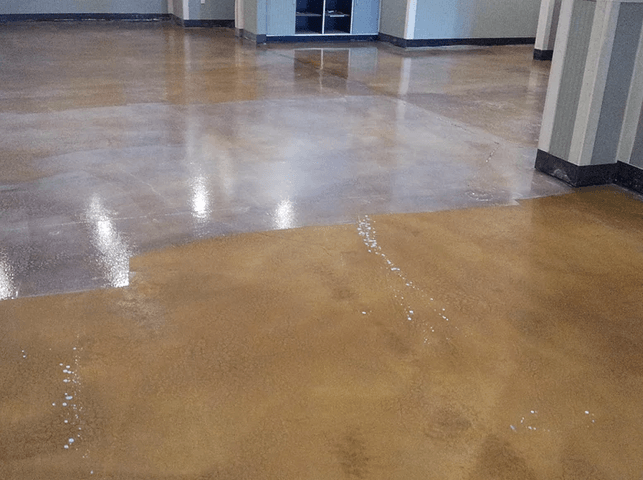 a shiny concrete floor in a room with a striped wall .