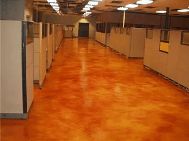 a long hallway with cubicles and a concrete floor