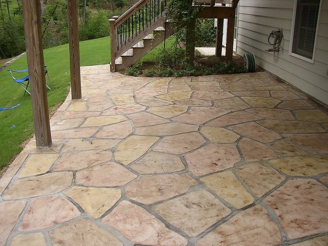 a patio with a wooden deck and stairs in the background .