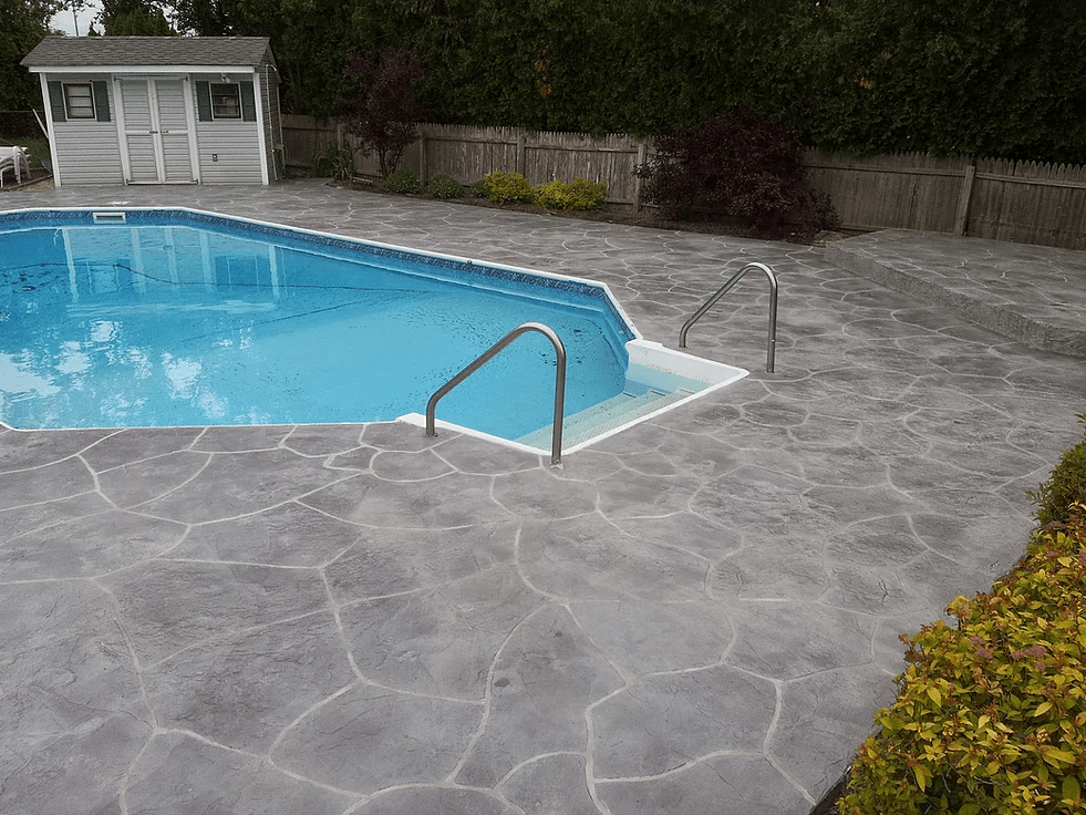a large swimming pool with stairs leading to it and a shed in the background .