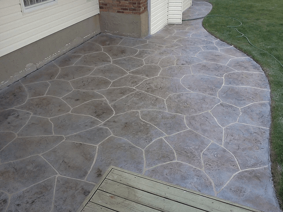 a concrete walkway with a wooden deck in front of a house