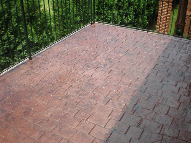 a balcony with a brick floor and a metal railing