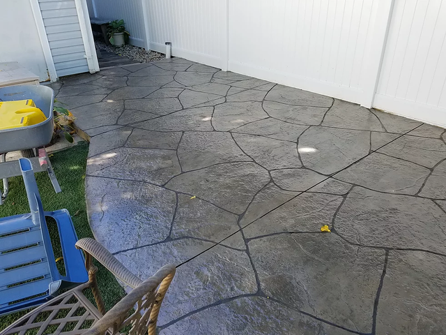 a concrete patio with a blue chair and a white fence .