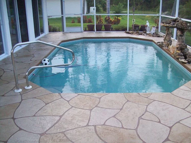 a large swimming pool is surrounded by a screened in porch