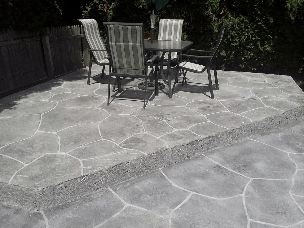 a black and white photo of a patio with a table and chairs .