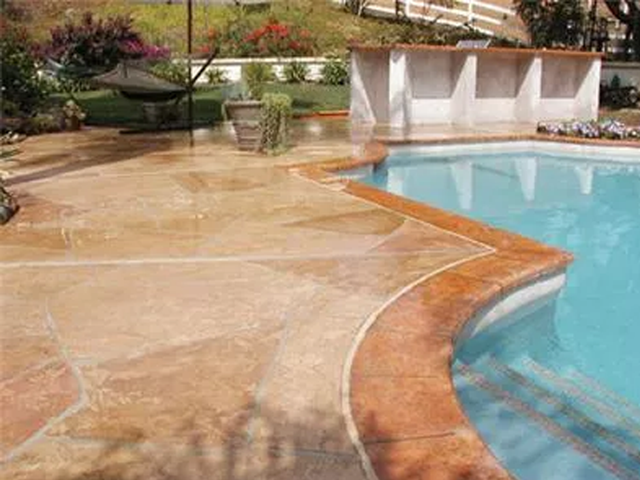 a large swimming pool with a patio in front of it .