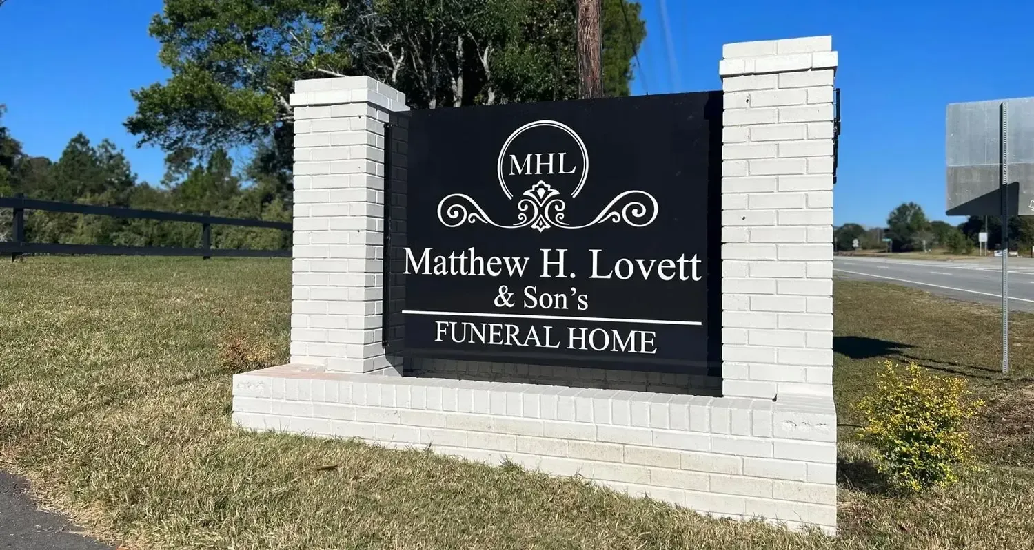 MHL Mathis H. Lovett & Sons Funeral Home sign on a brick monument by a roadside