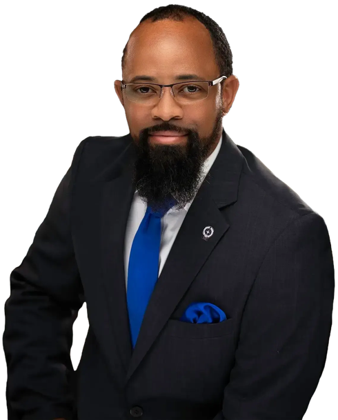 Man in a dark suit with blue tie and pocket square, posing against a white background.