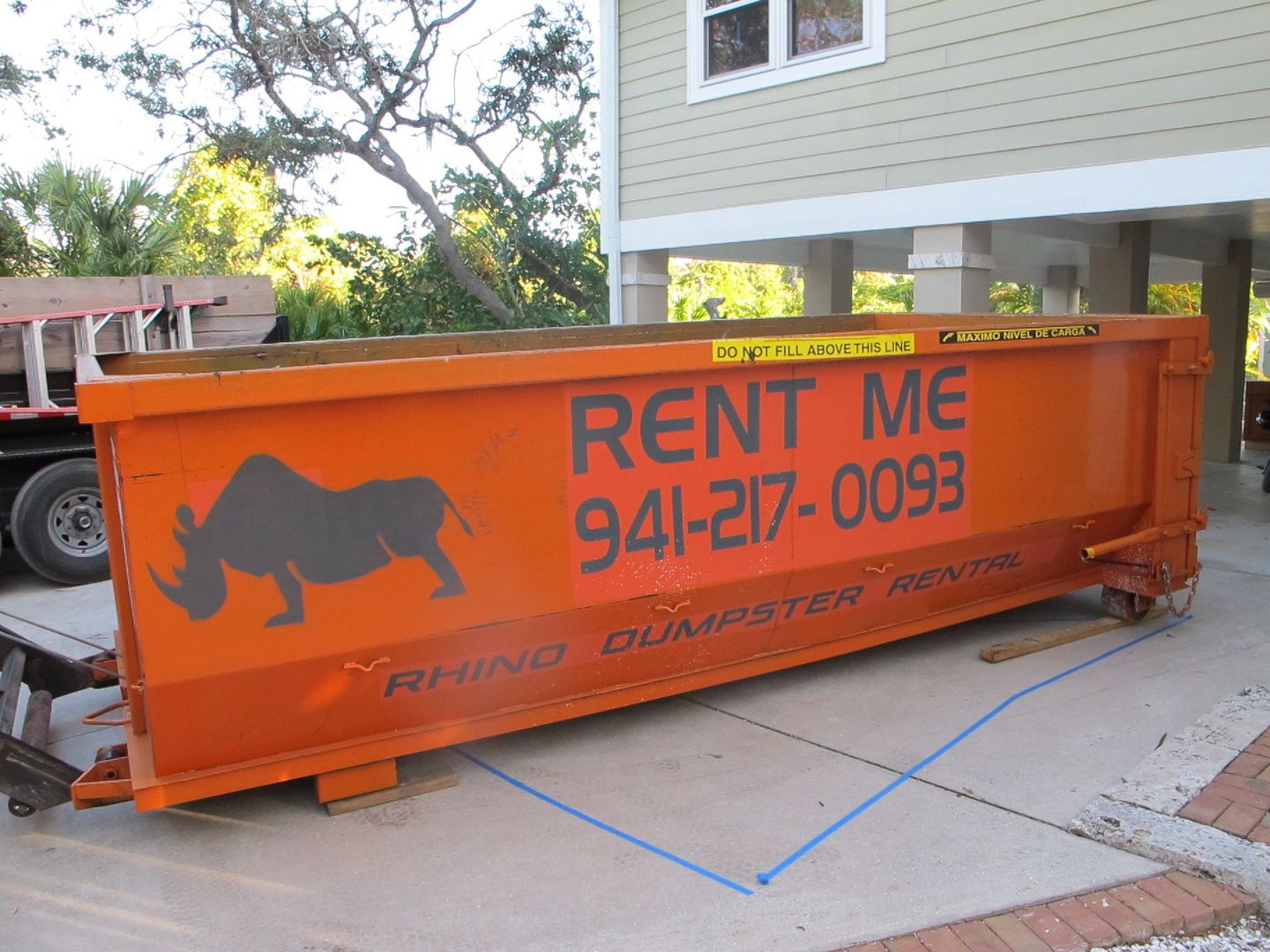Two orange dumpsters are parked in front of a house.