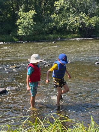 A group of people walking along a river near trees