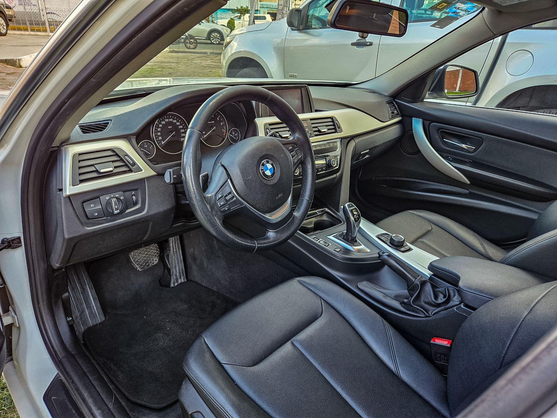 Interior de un automóvil BMW con asientos, tablero y volante de cuero negro.