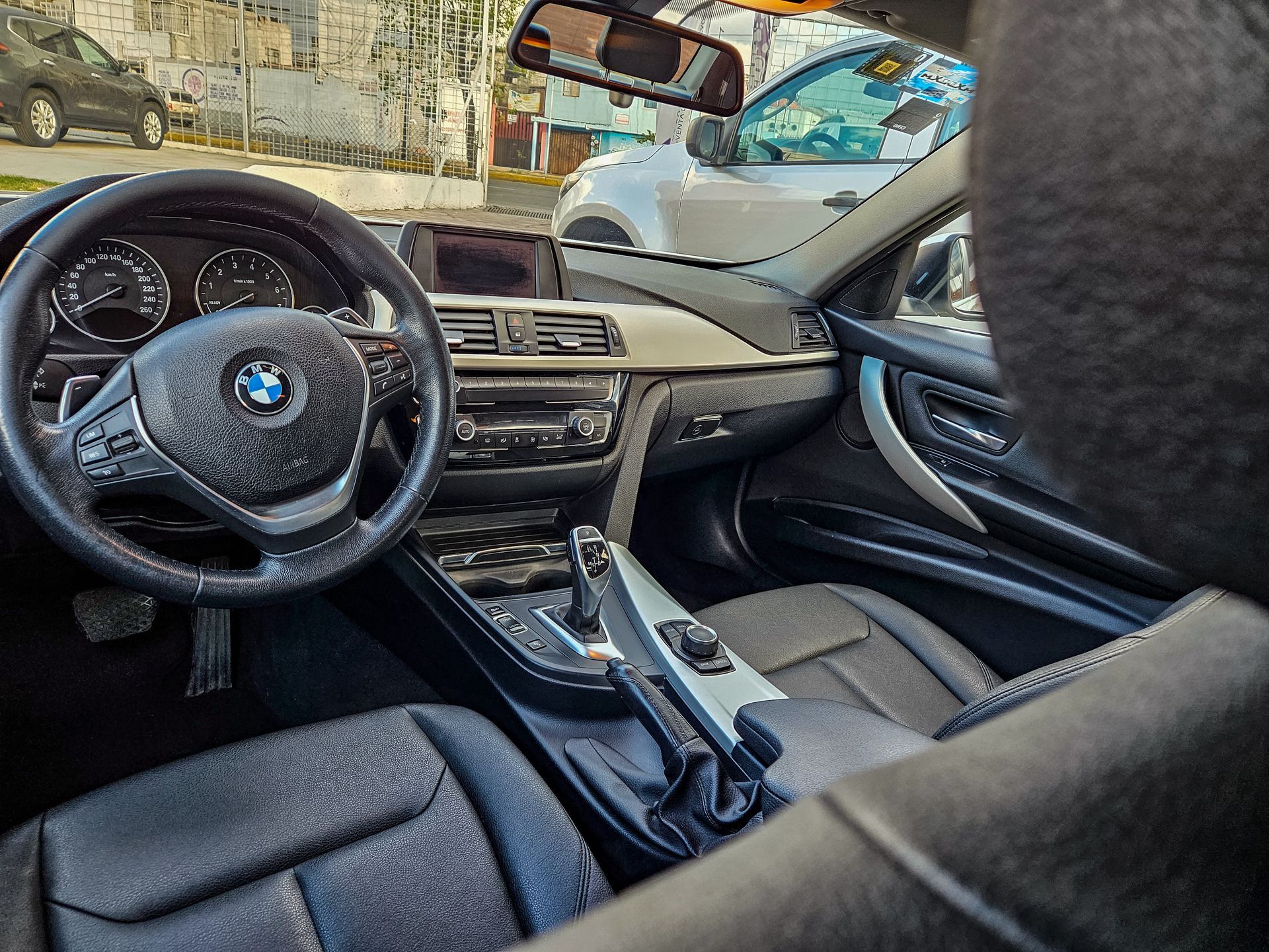 Vista interior de un automóvil BMW con asientos, volante y tablero de cuero negro.