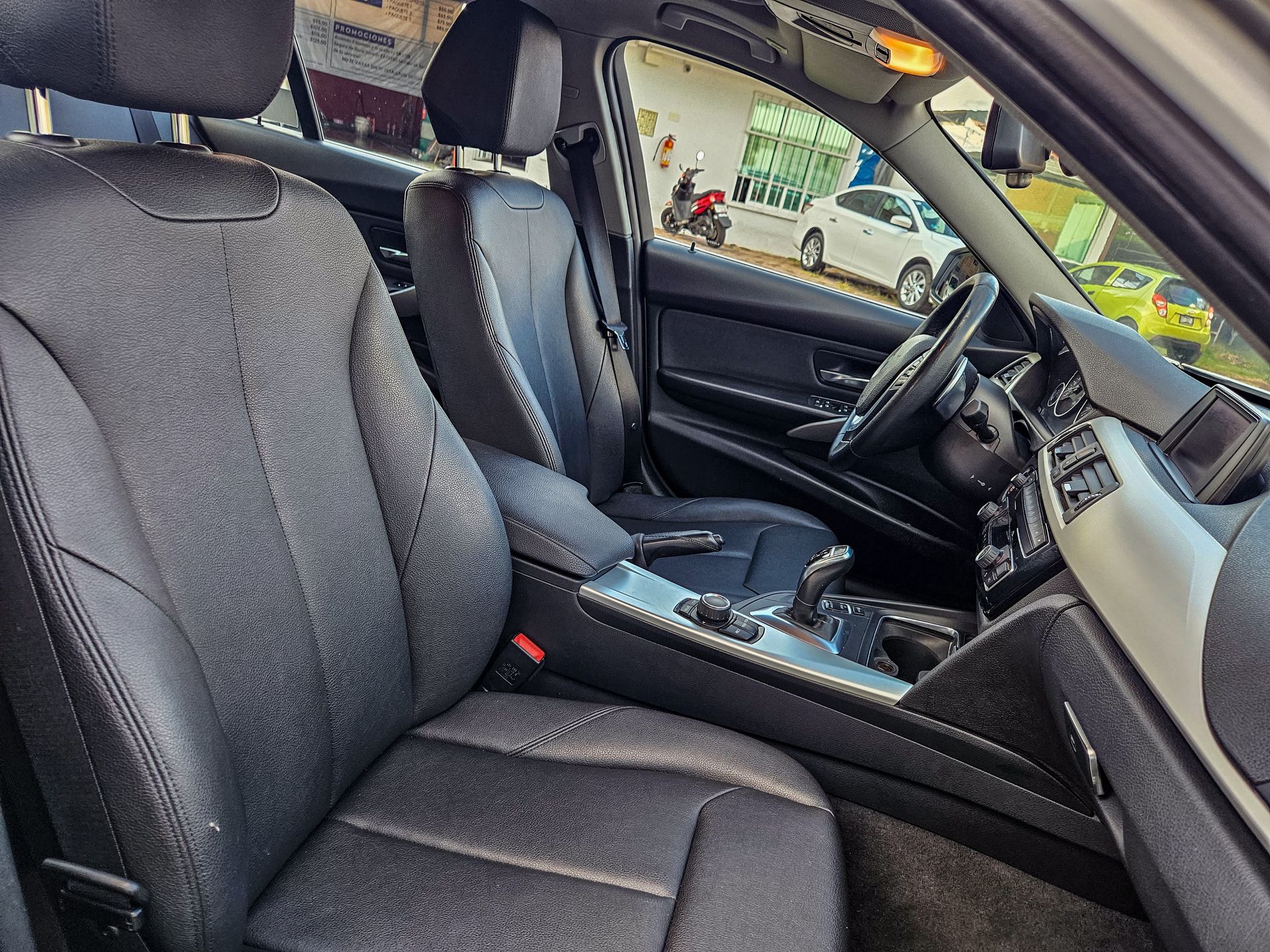 Interior negro de un coche, incluyendo asientos, salpicadero y volante. La luz del sol entra a raudales.