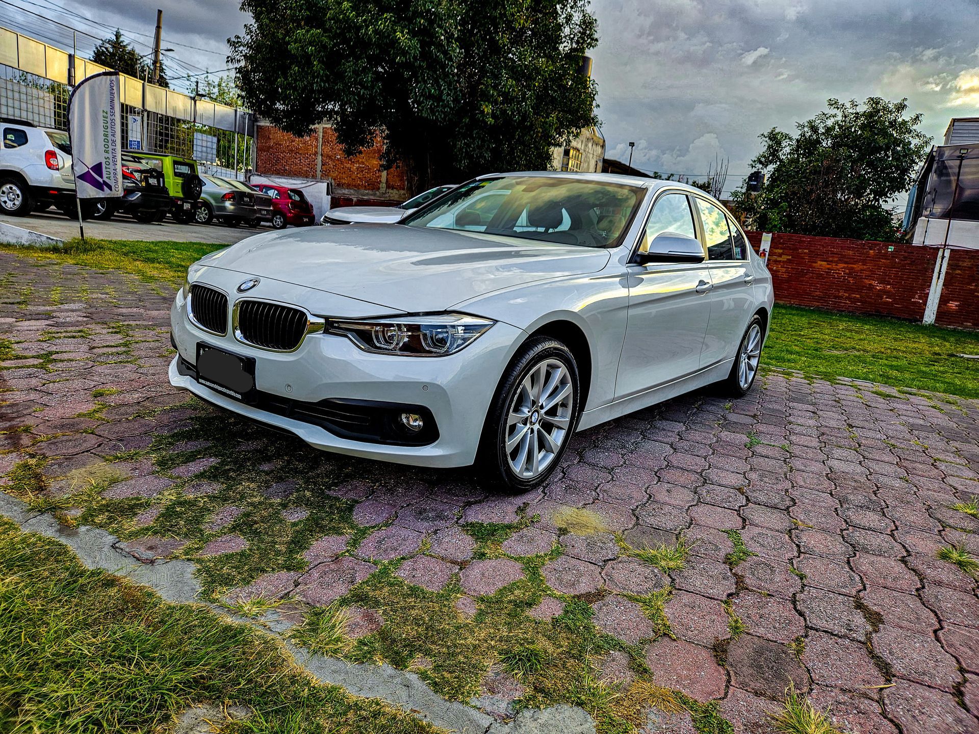 Un sedán BMW blanco estacionado sobre una superficie adoquinada.