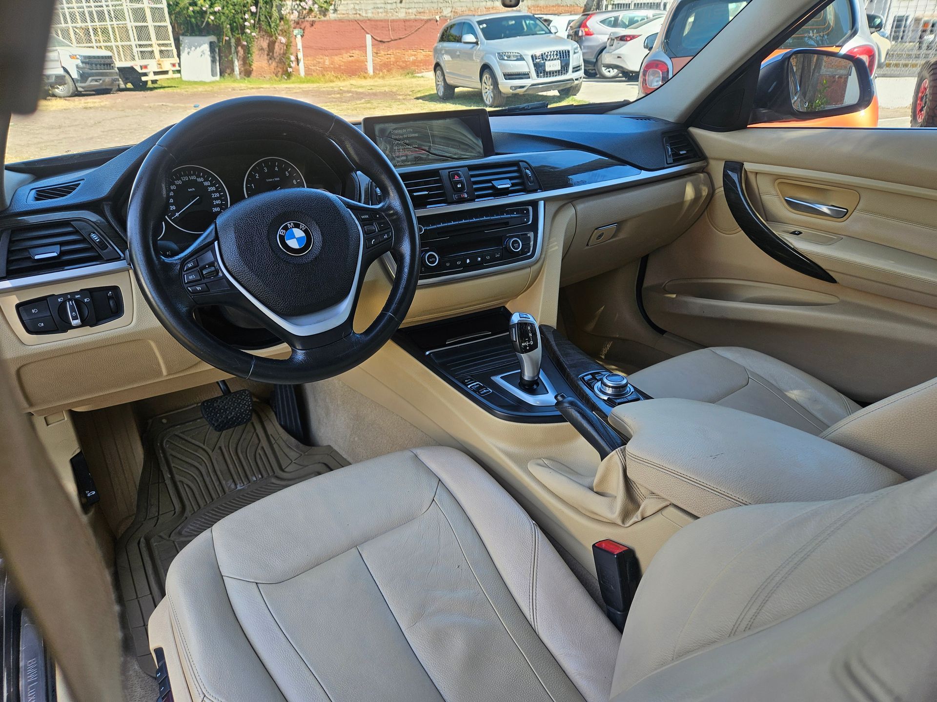 Interior del automóvil BMW de color bronce con tablero y volante negros; se ve una consola central.