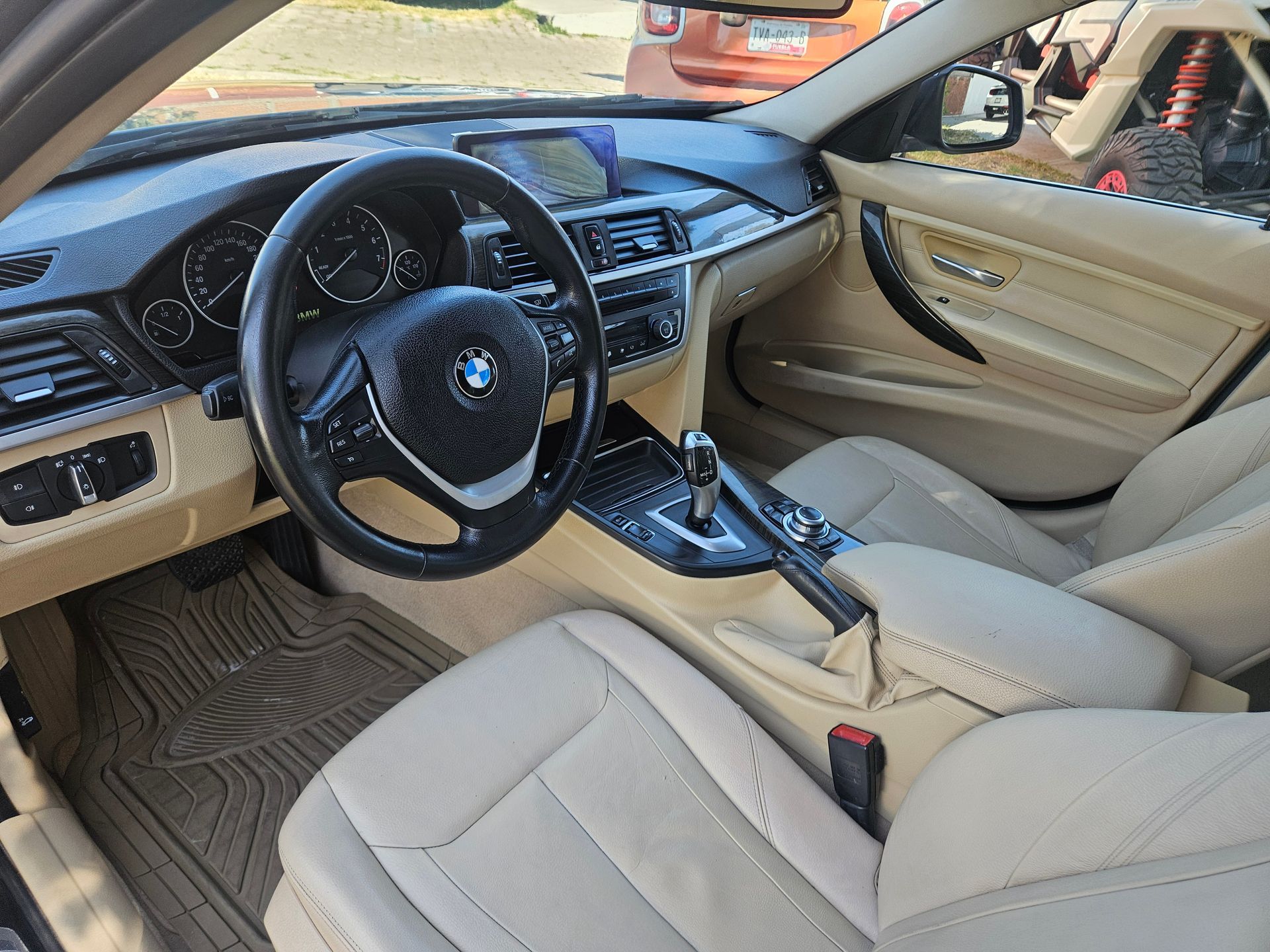 Interior color canela de un automóvil BMW, que muestra el tablero, el volante, los asientos y la consola central.