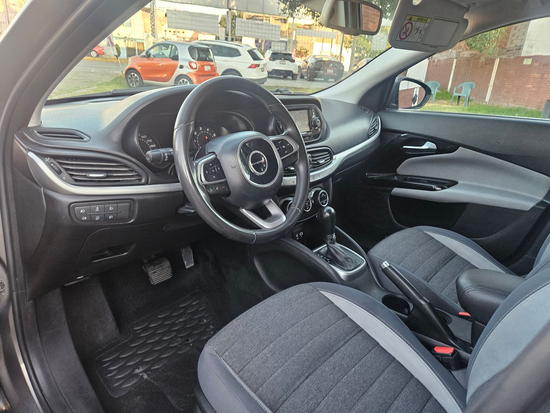 Interior de un automóvil con asientos y tablero de instrumentos en color negro y gris, volante visible.