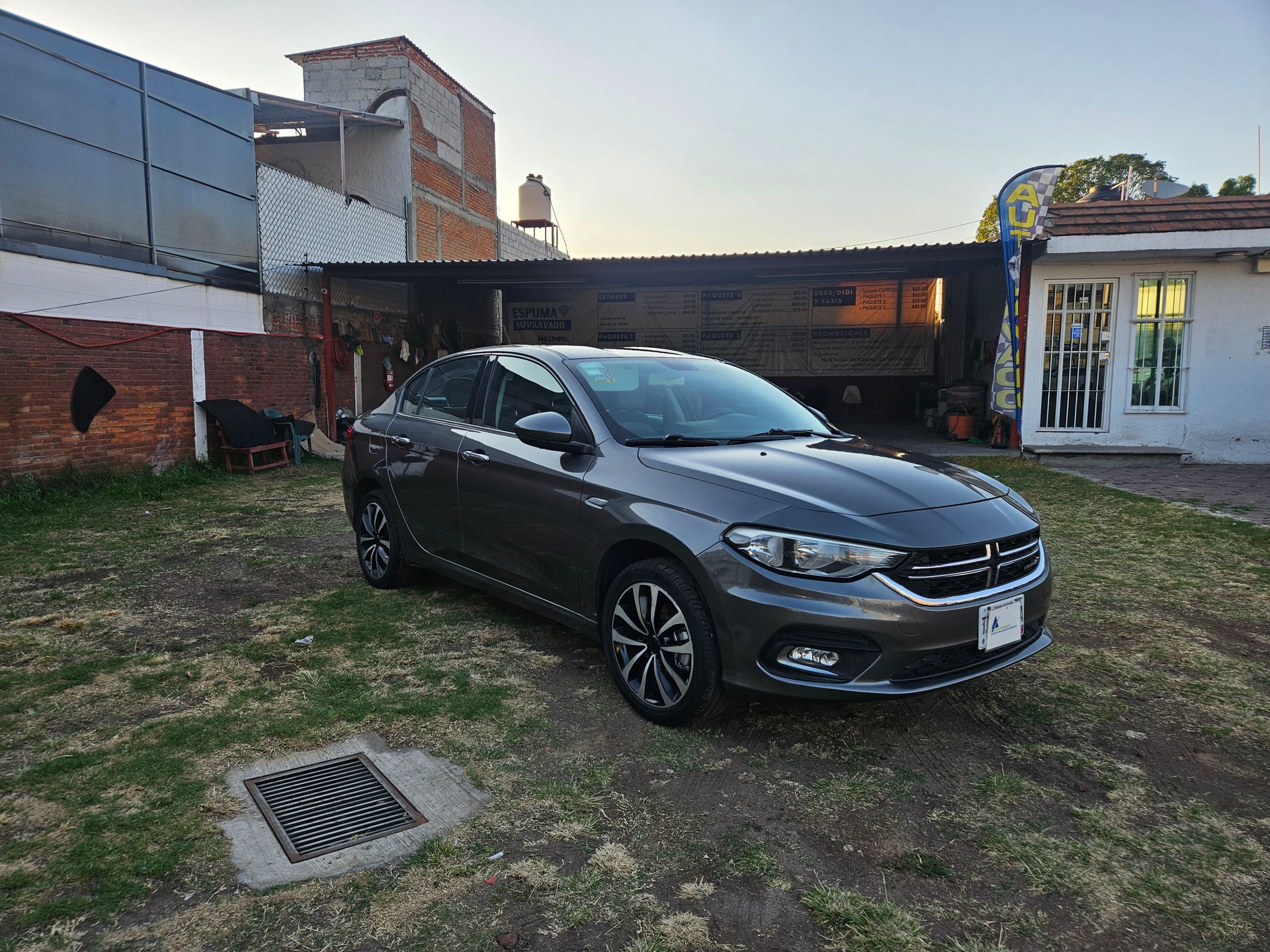 Un sedán Dodge Neon gris estacionado en el césped frente a una casa.