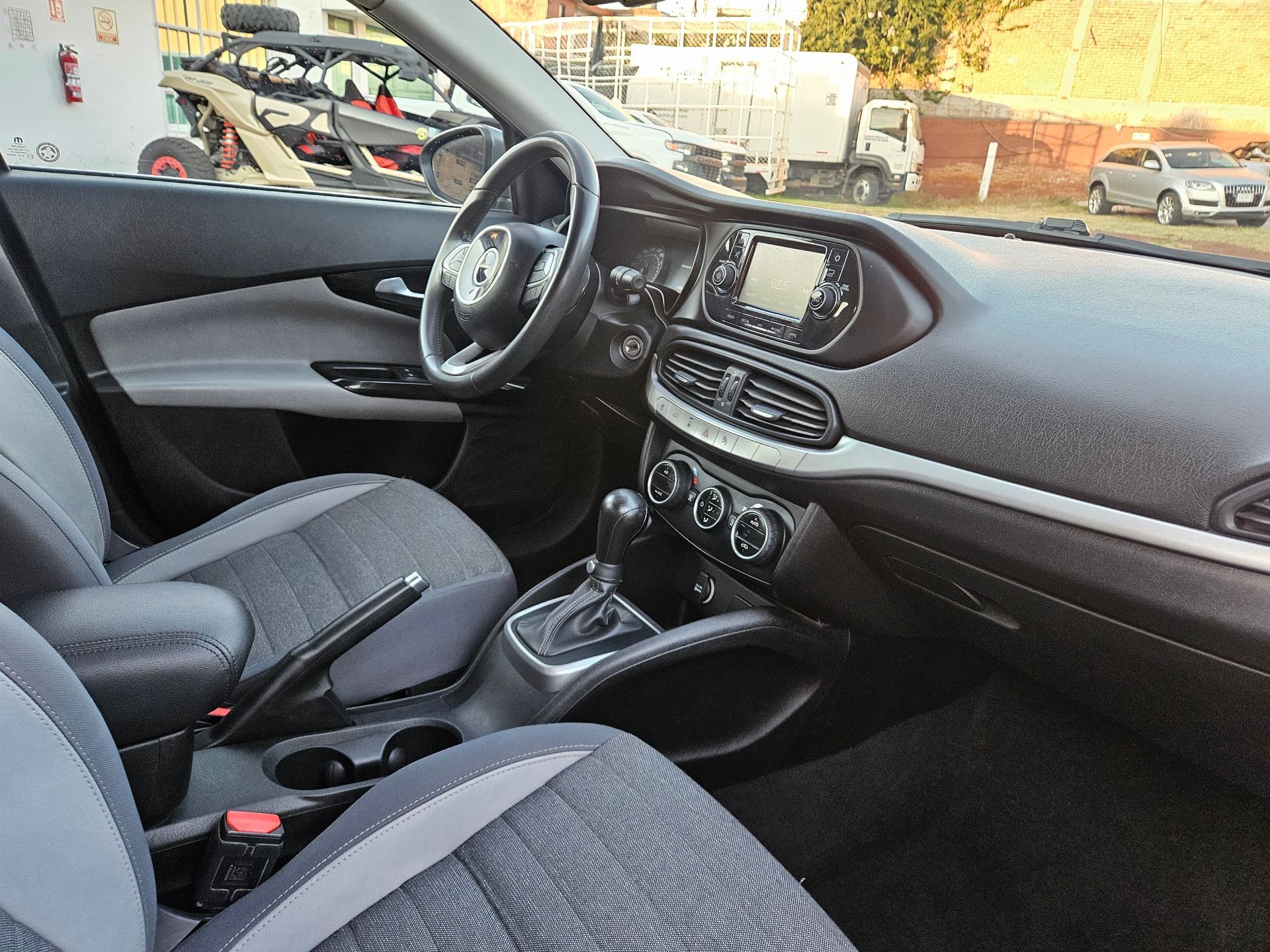 Interior de un automóvil gris y negro que muestra el tablero, el volante, los asientos y la palanca de cambios.