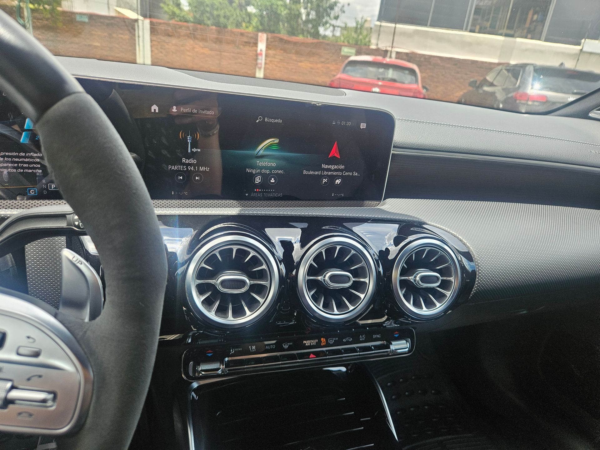 Interior de un Mercedes-Benz de color negro con volante y salpicadero con pantallas y salidas de aire.
