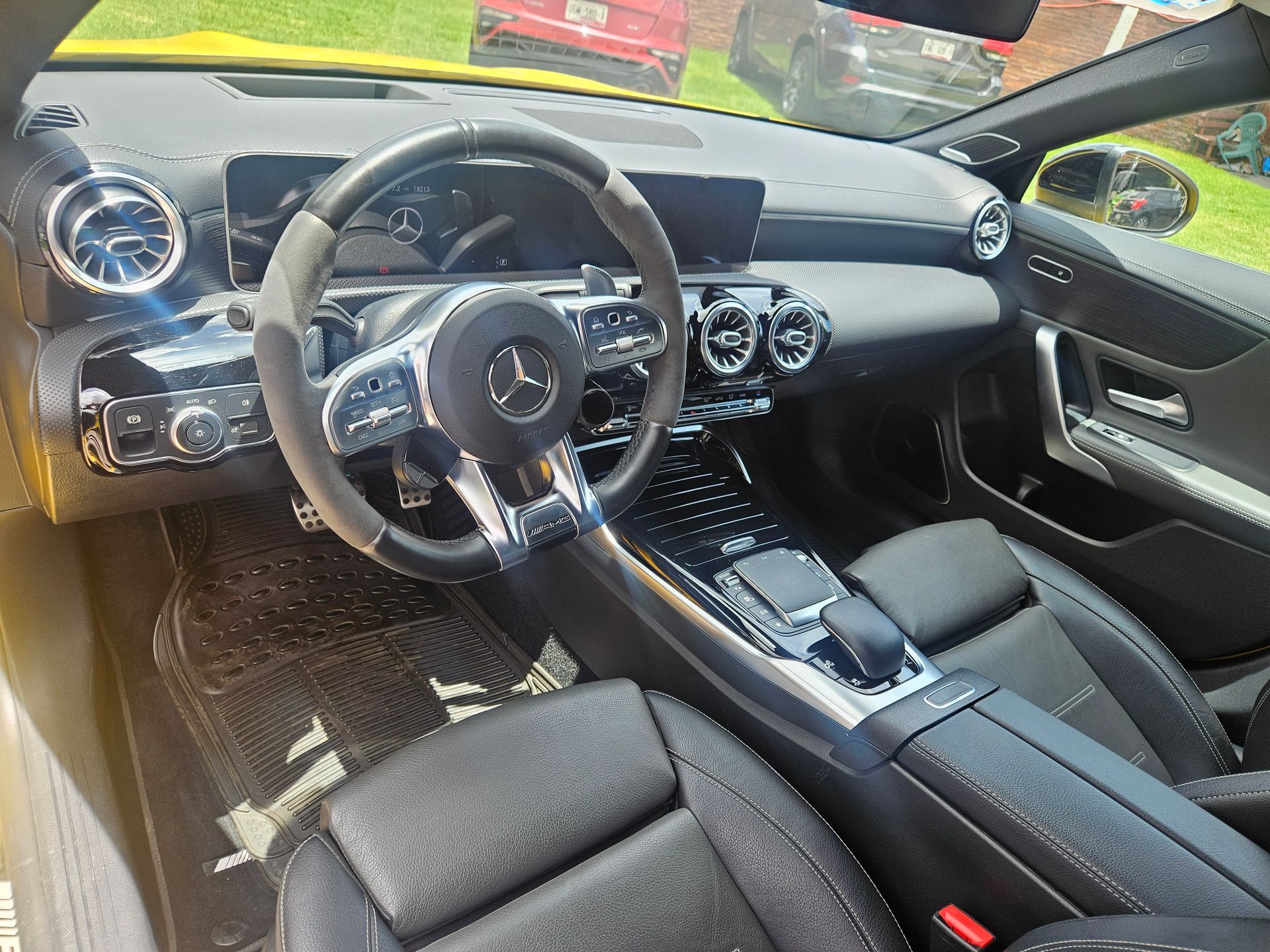 Interior negro de un Mercedes-Benz amarillo, que muestra el tablero, el volante y los asientos.