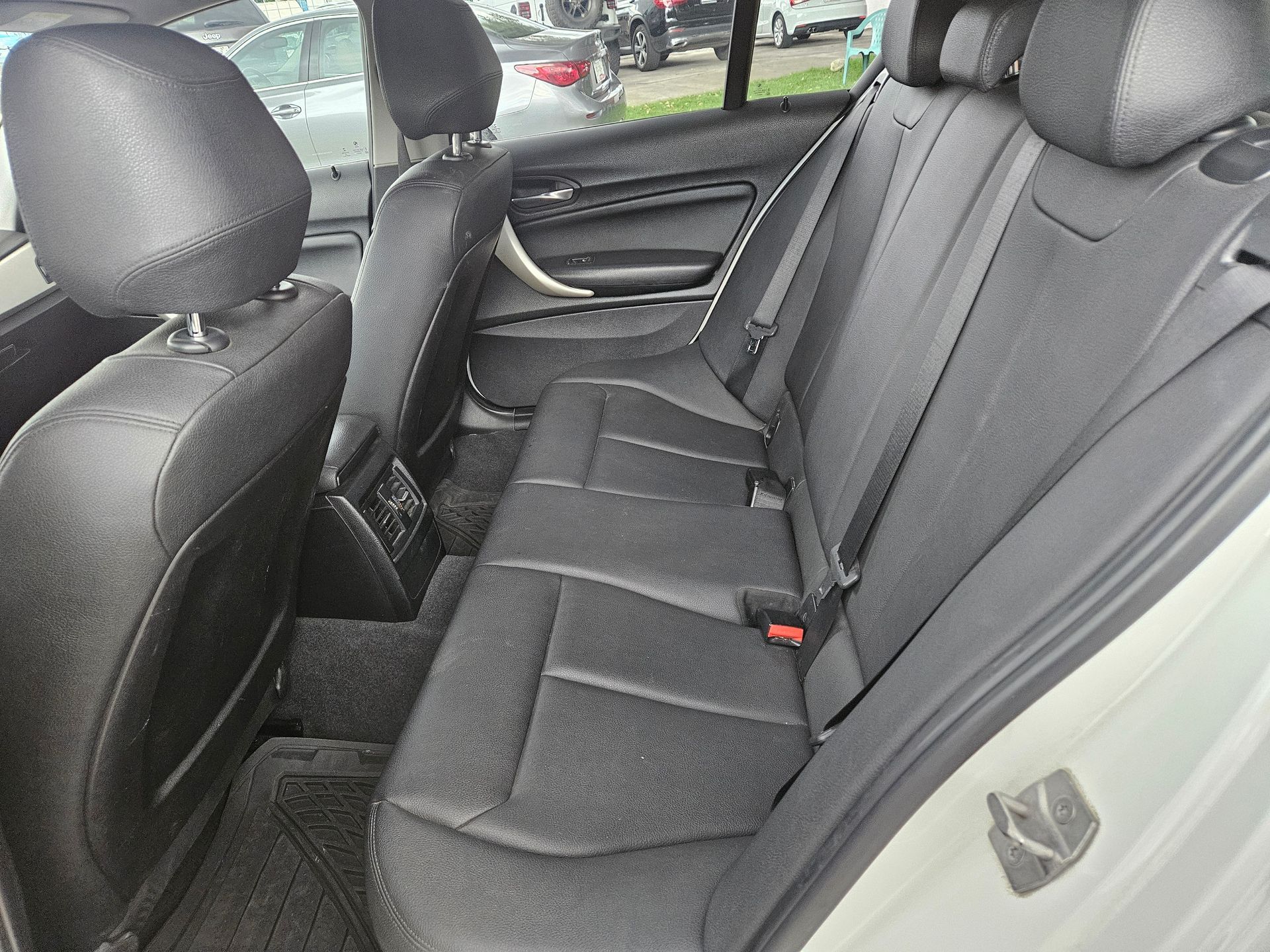 Interior trasero de un automóvil, mostrando asientos y reposacabezas de cuero negro.