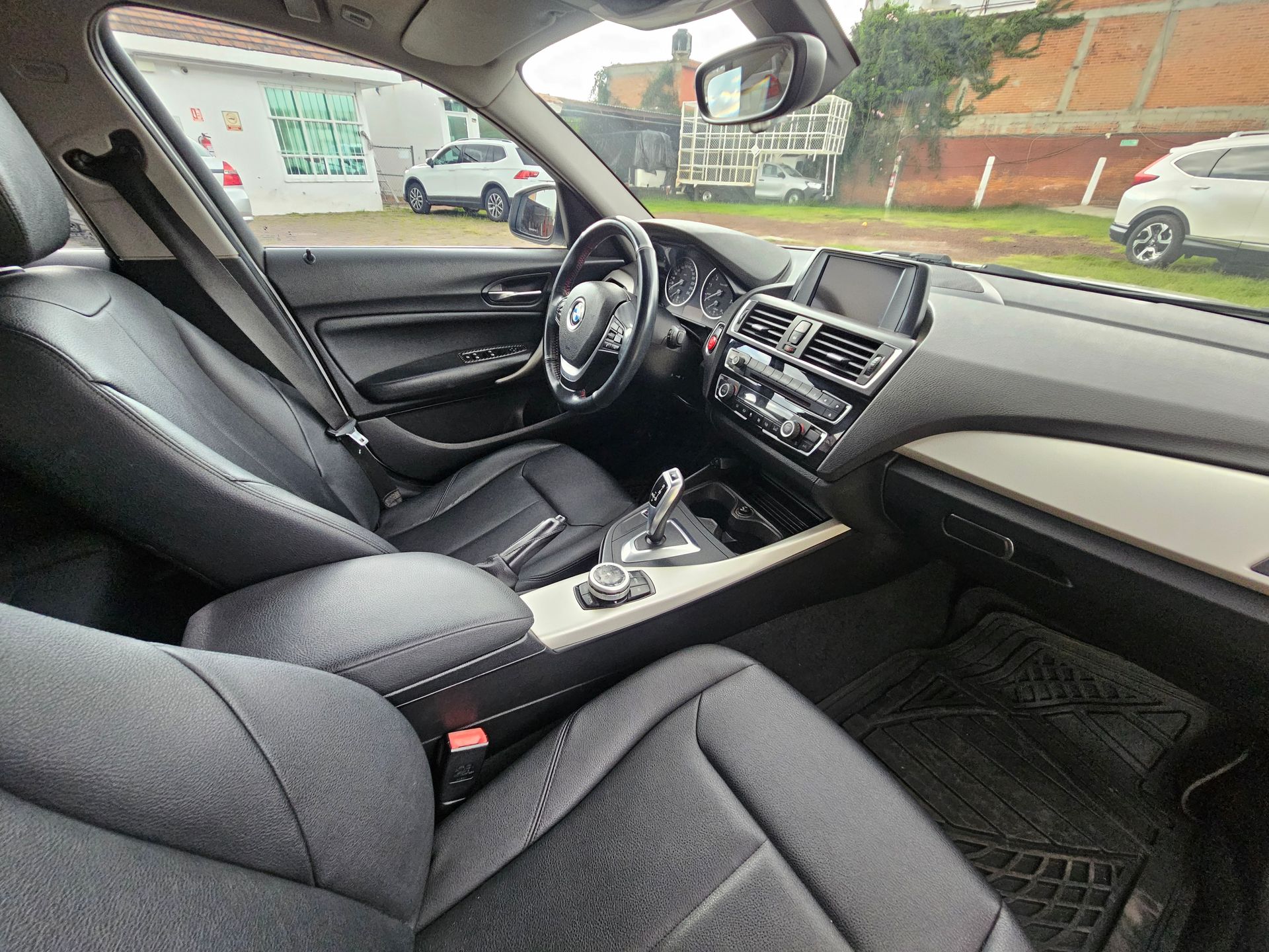 Interior negro de un automóvil BMW, que muestra el tablero, los asientos, el volante y la palanca de cambios.