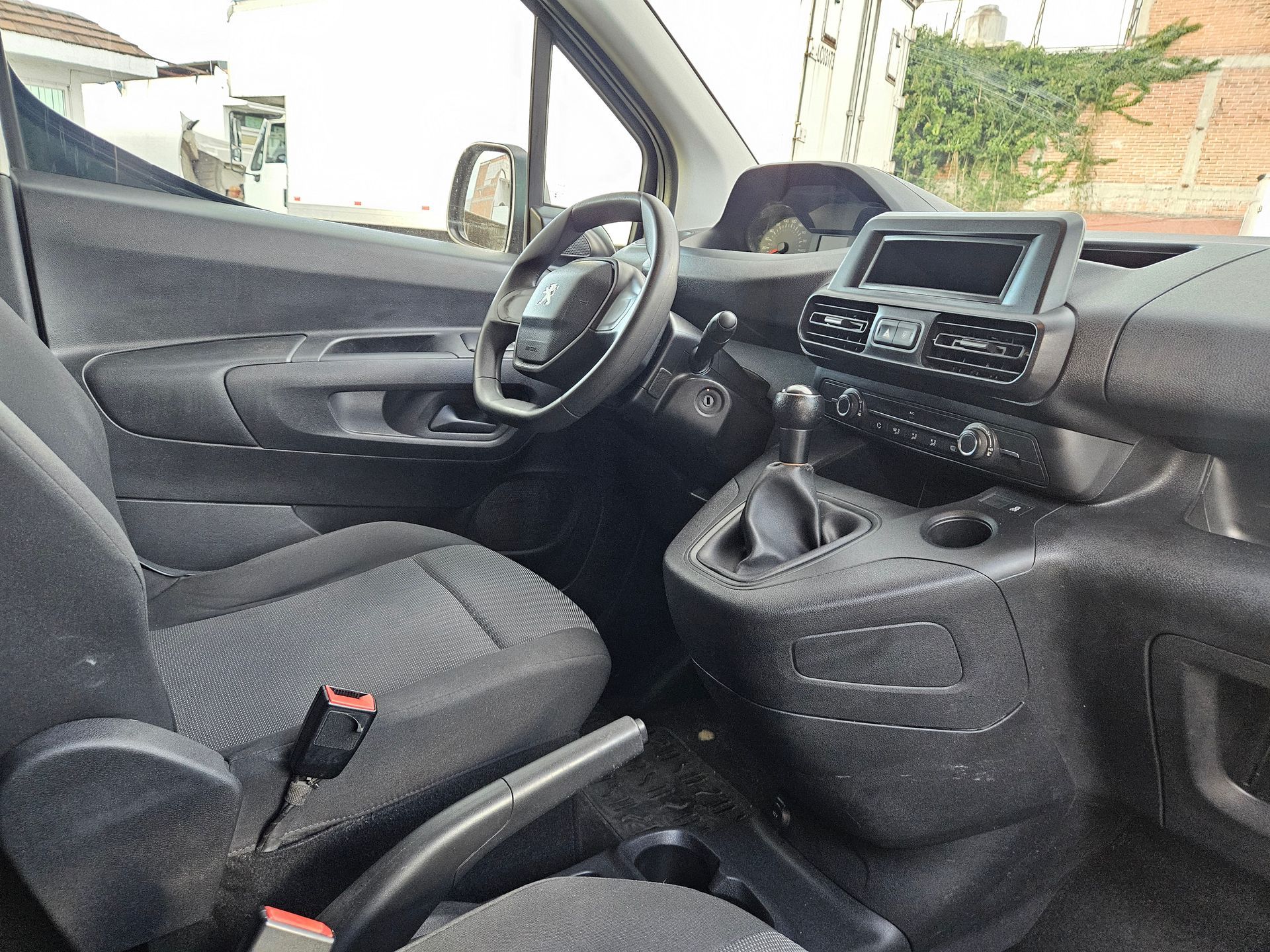 Vista interior de un automóvil negro con volante, tablero y asientos.