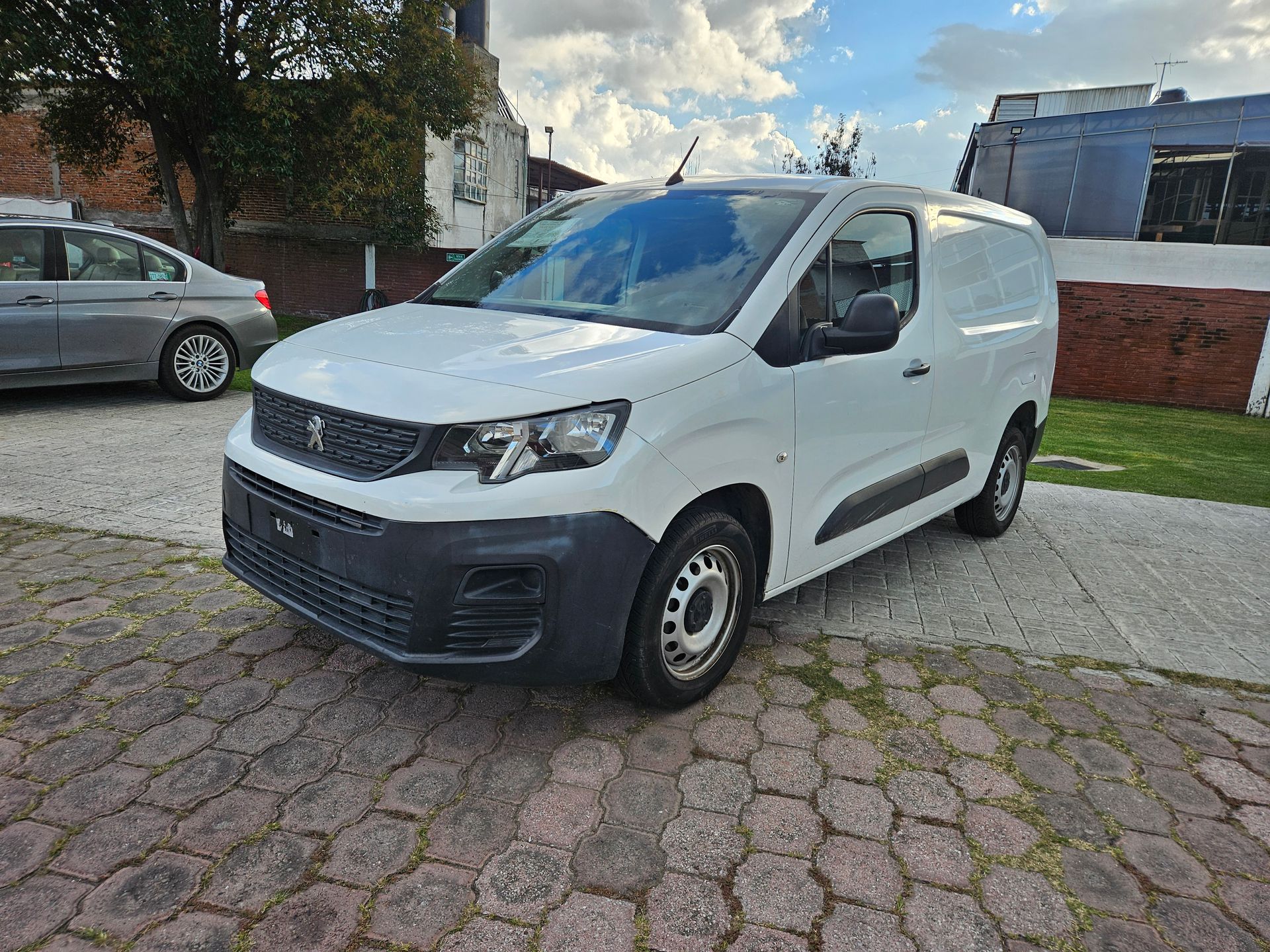Furgoneta Peugeot Partner de color blanco aparcada sobre adoquines.