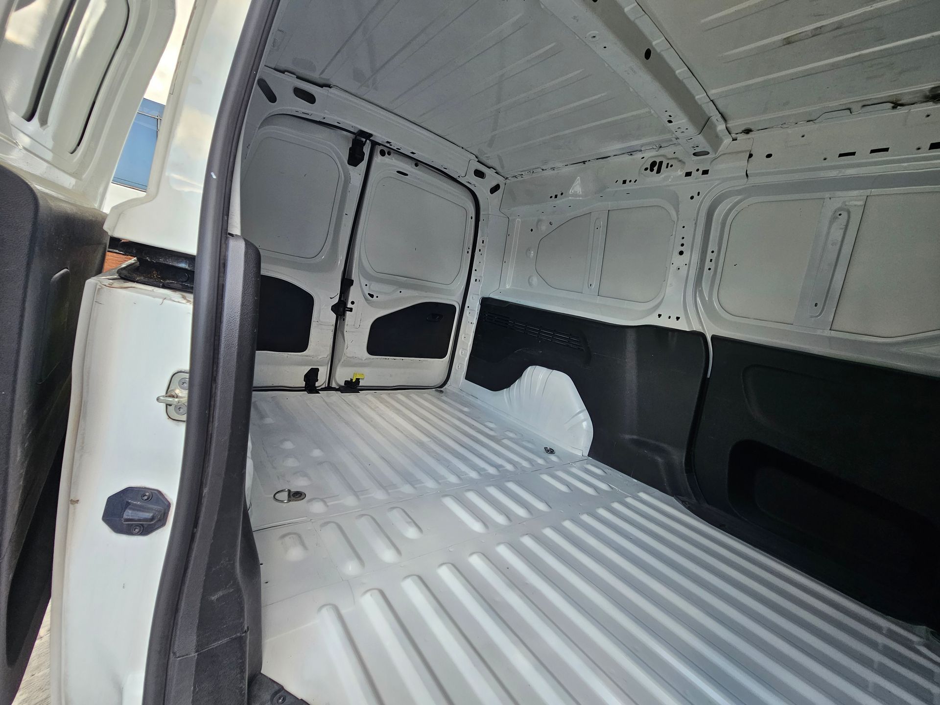 Interior de camioneta de carga blanca vacía con piso acanalado y ventanas de paneles laterales.
