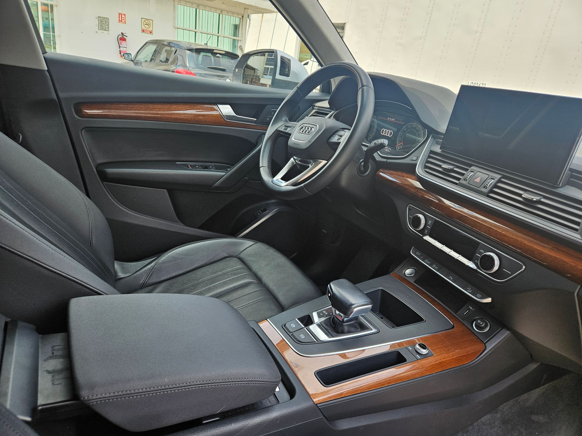 Interior de un SUV de Audi con asientos negros, molduras de madera y consola central.