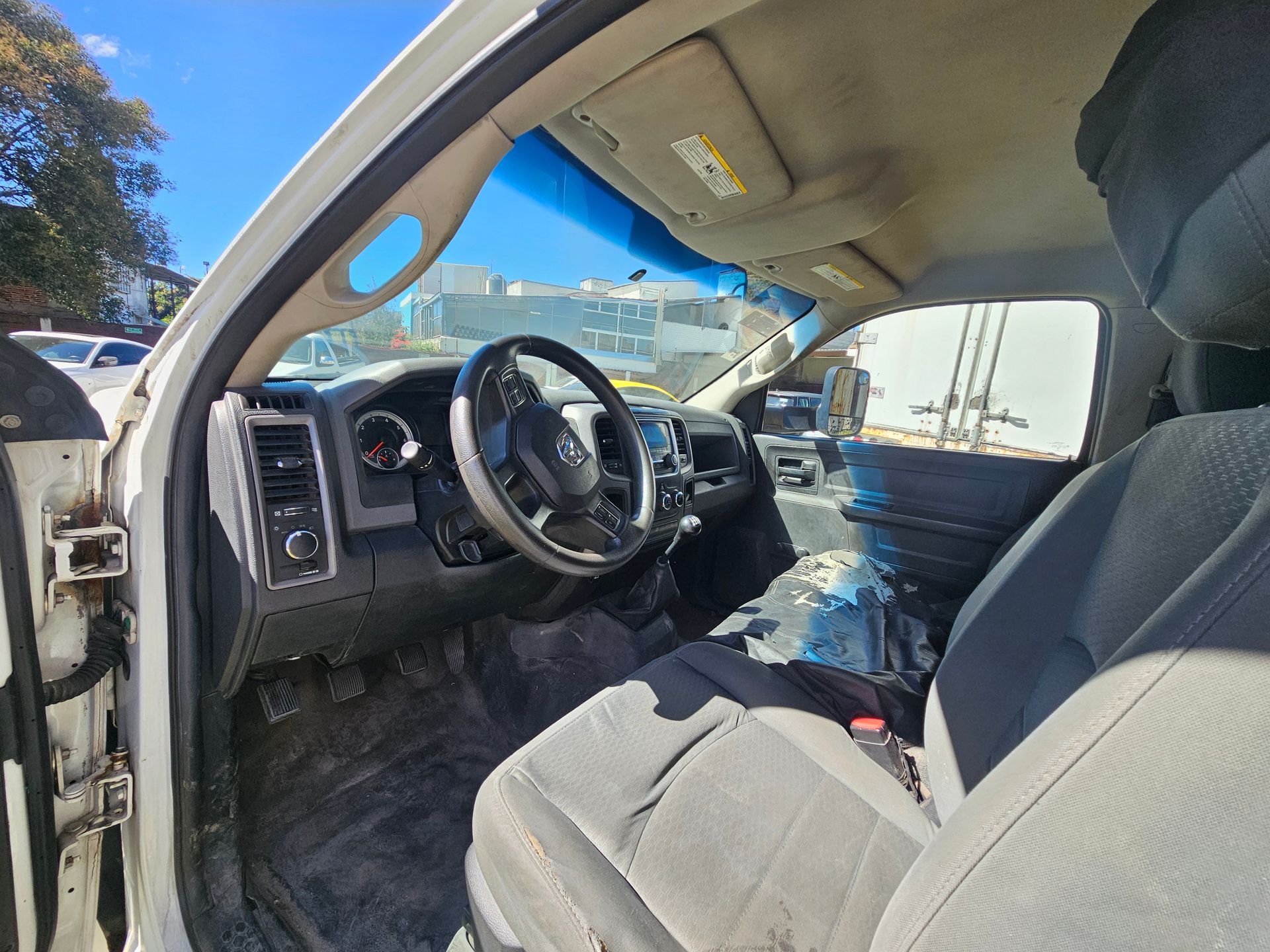 Interior de una camioneta blanca, que muestra el tablero, el volante y los asientos delanteros.