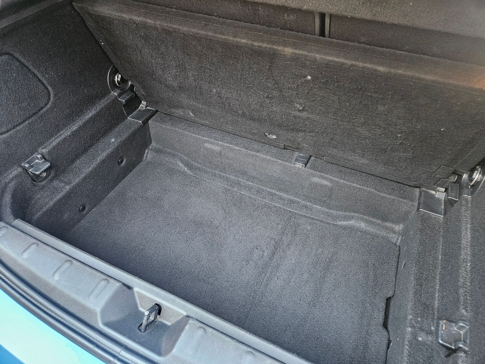 Maletero de coche vacío forrado con alfombra gris oscuro.