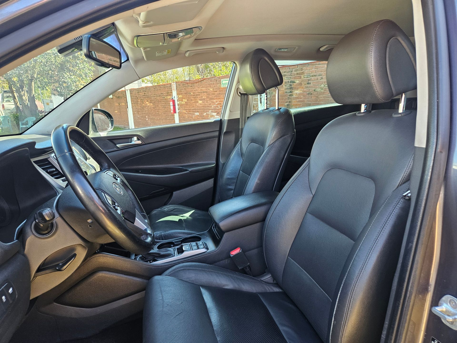 Interior de cuero negro de un automóvil; asientos delanteros y volante visibles.