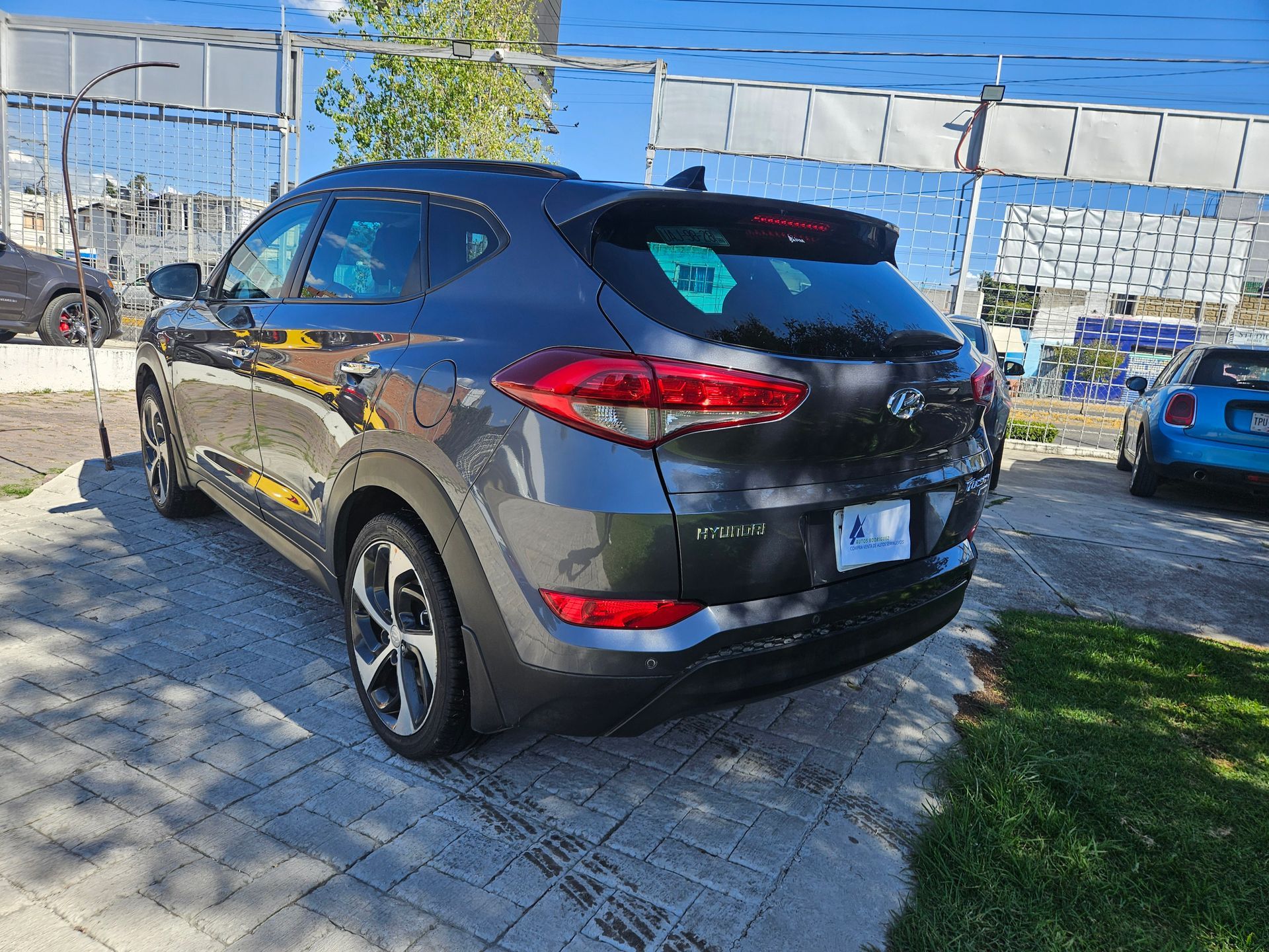 SUV Hyundai Tucson gris oscuro estacionado al aire libre en un día soleado.