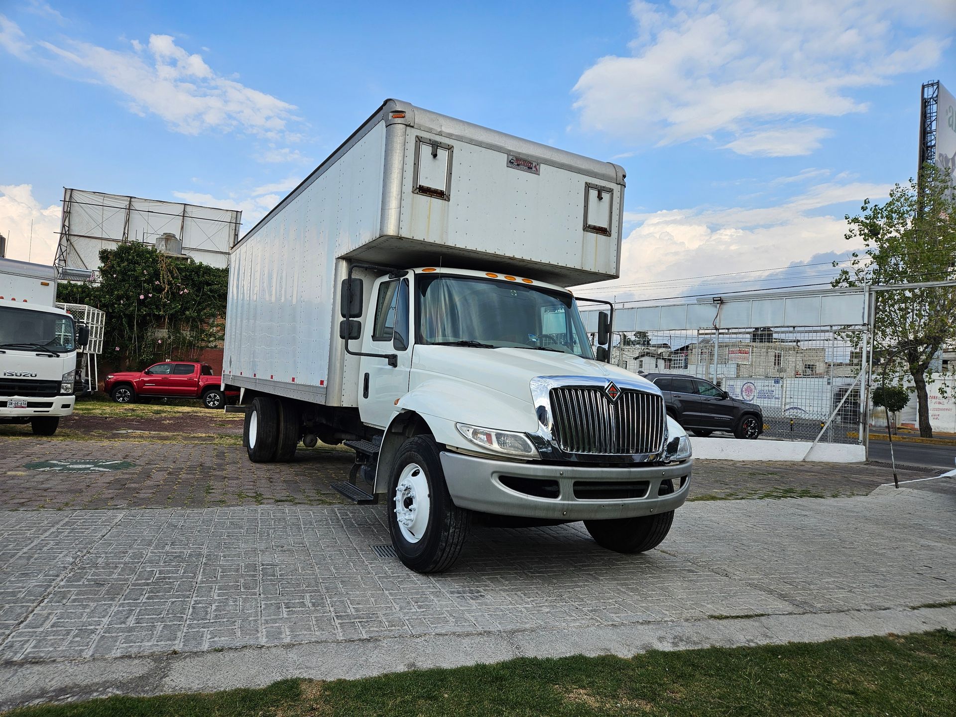 Camión de caja blanca estacionado en un lote pavimentado bajo un cielo nublado.