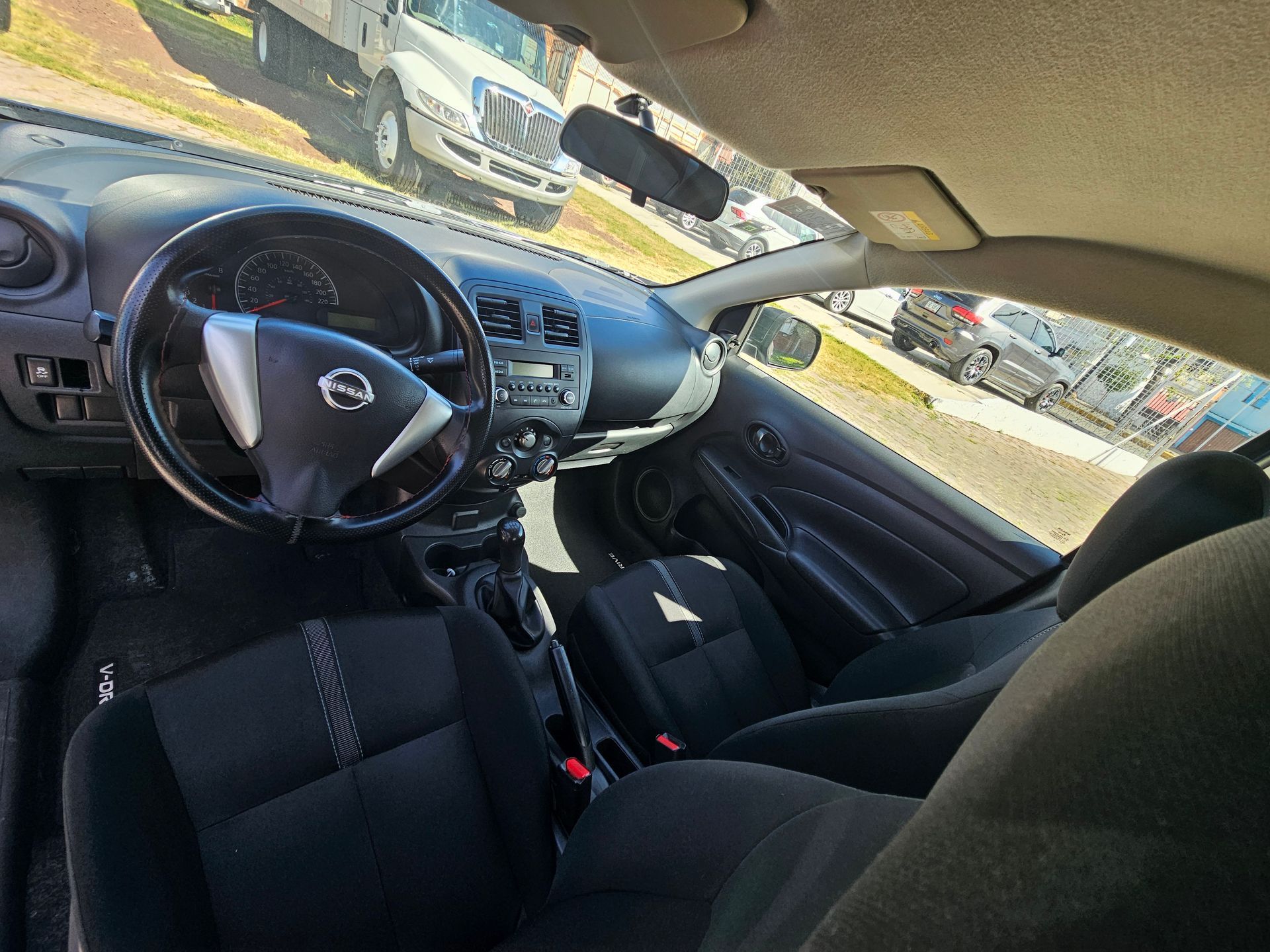 Interior de un vehículo Nissan negro, que muestra el volante, el tablero y los asientos.
