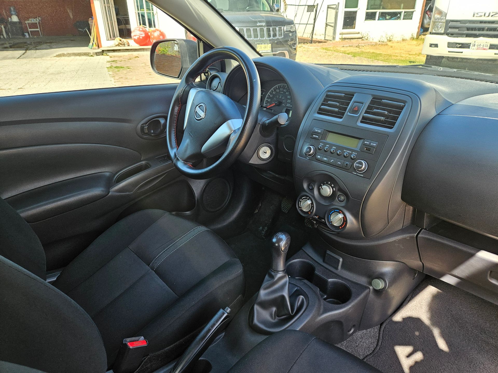 Vista interior de un automóvil Nissan negro, que muestra el tablero, el volante, los asientos y la palanca de cambios.