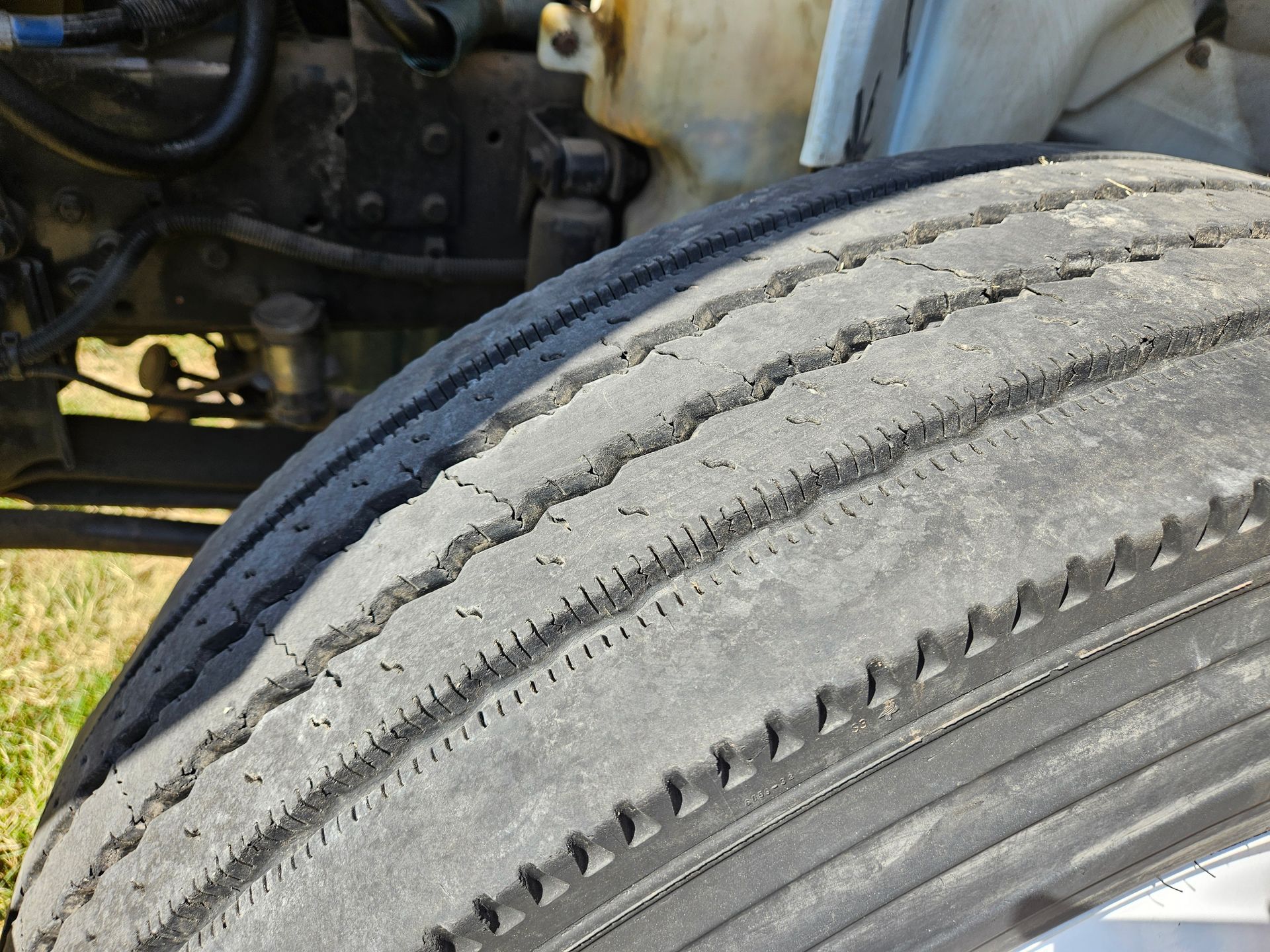 Primer plano de un neumático de camión desgastado con la banda de rodadura agrietada.