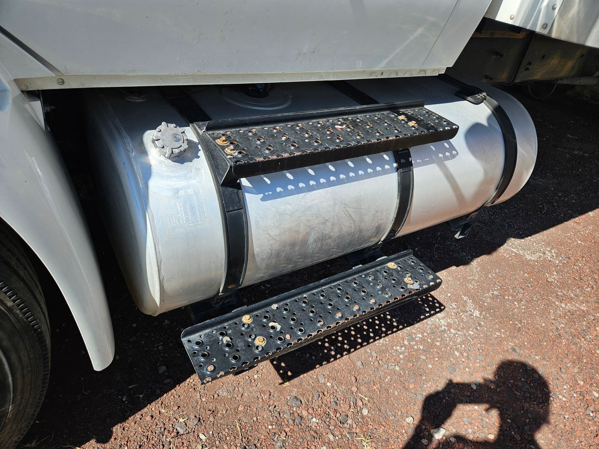 Tanque de combustible de camión con dos escalones de metal negros adjuntos para acceder.