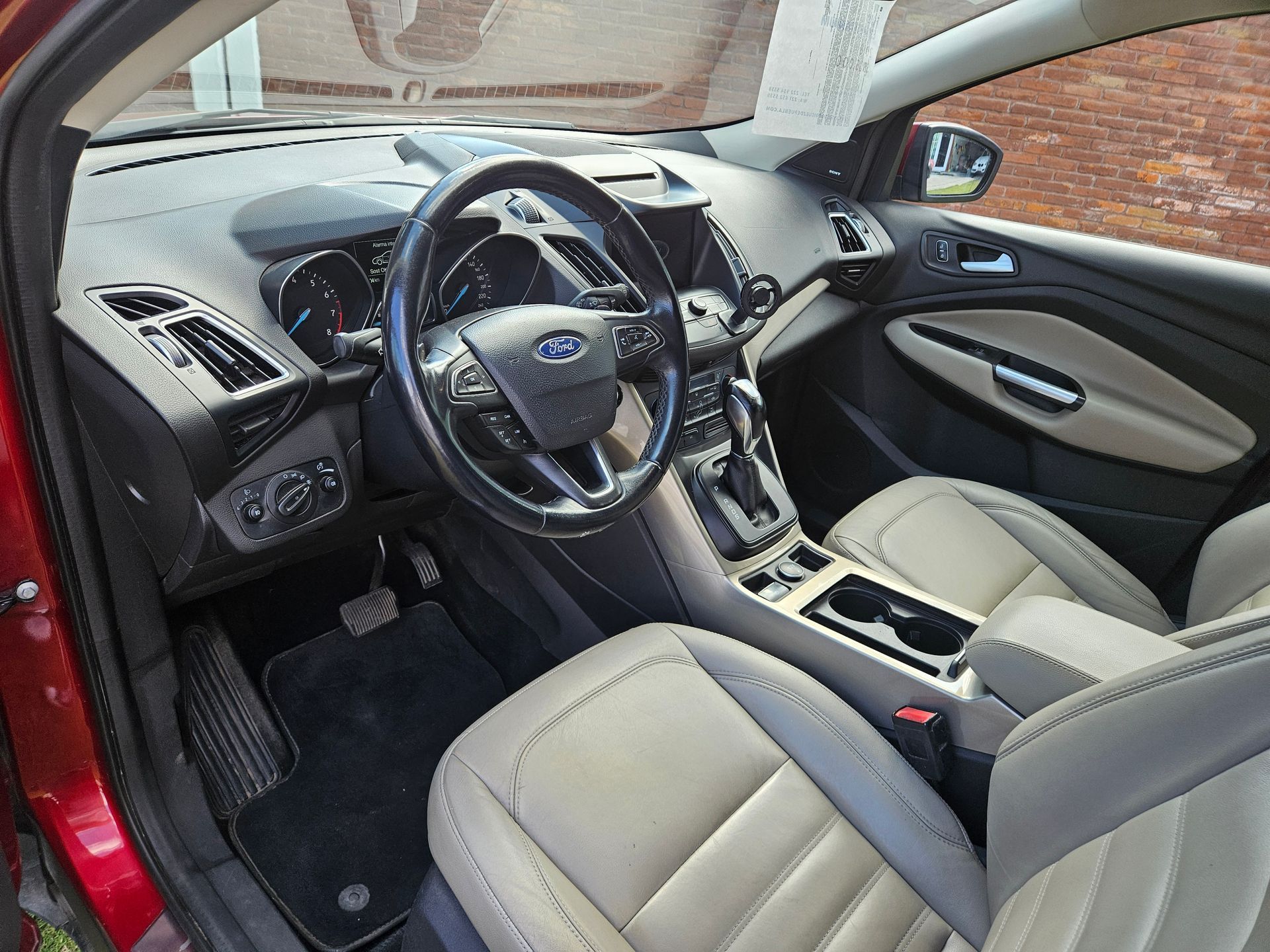 Vista interior de una Ford Escape roja. Cuenta con volante negro, asientos color canela y consola central.